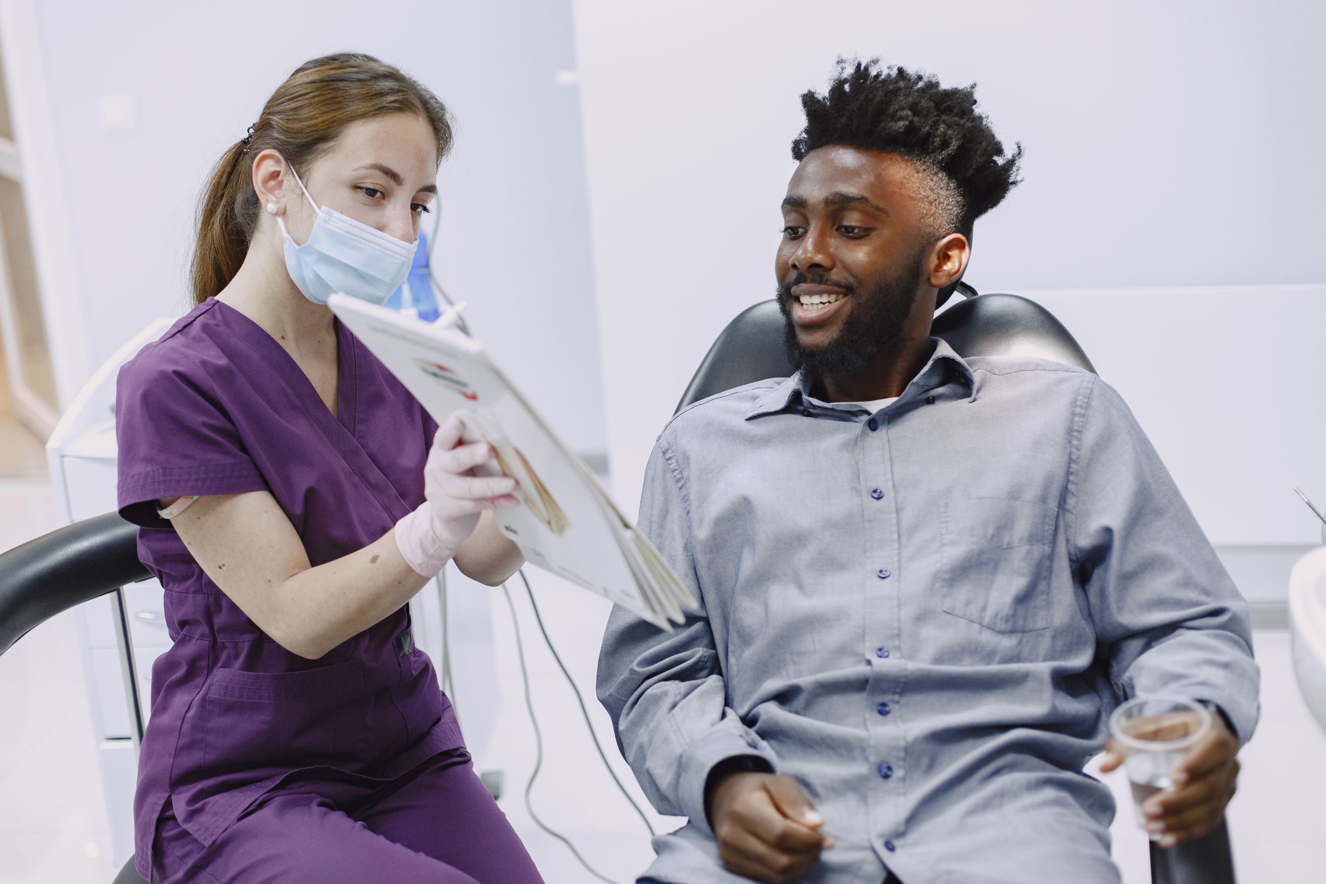 A smiling patient in the dental chair going over his treatment plan with a clinician