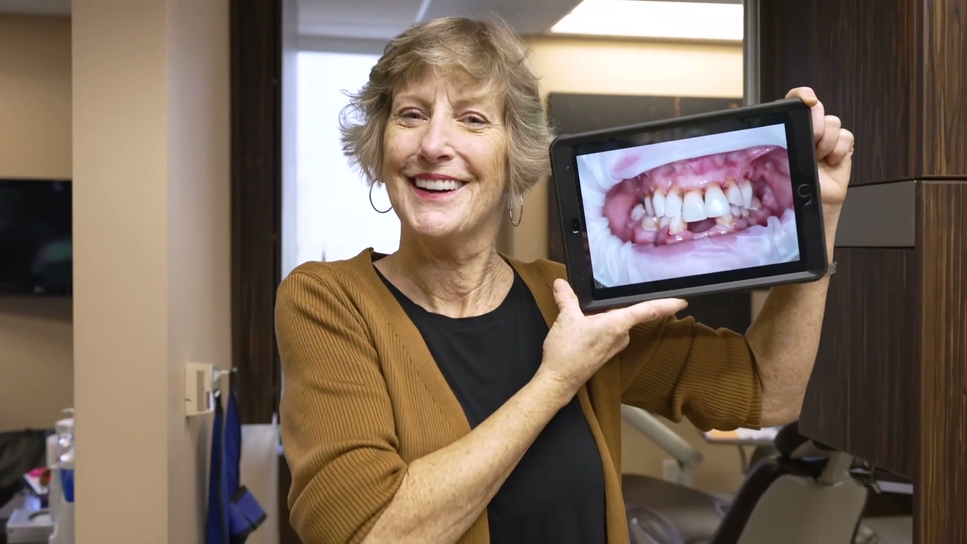 Leslie holding up a photo of her new full-arch smile